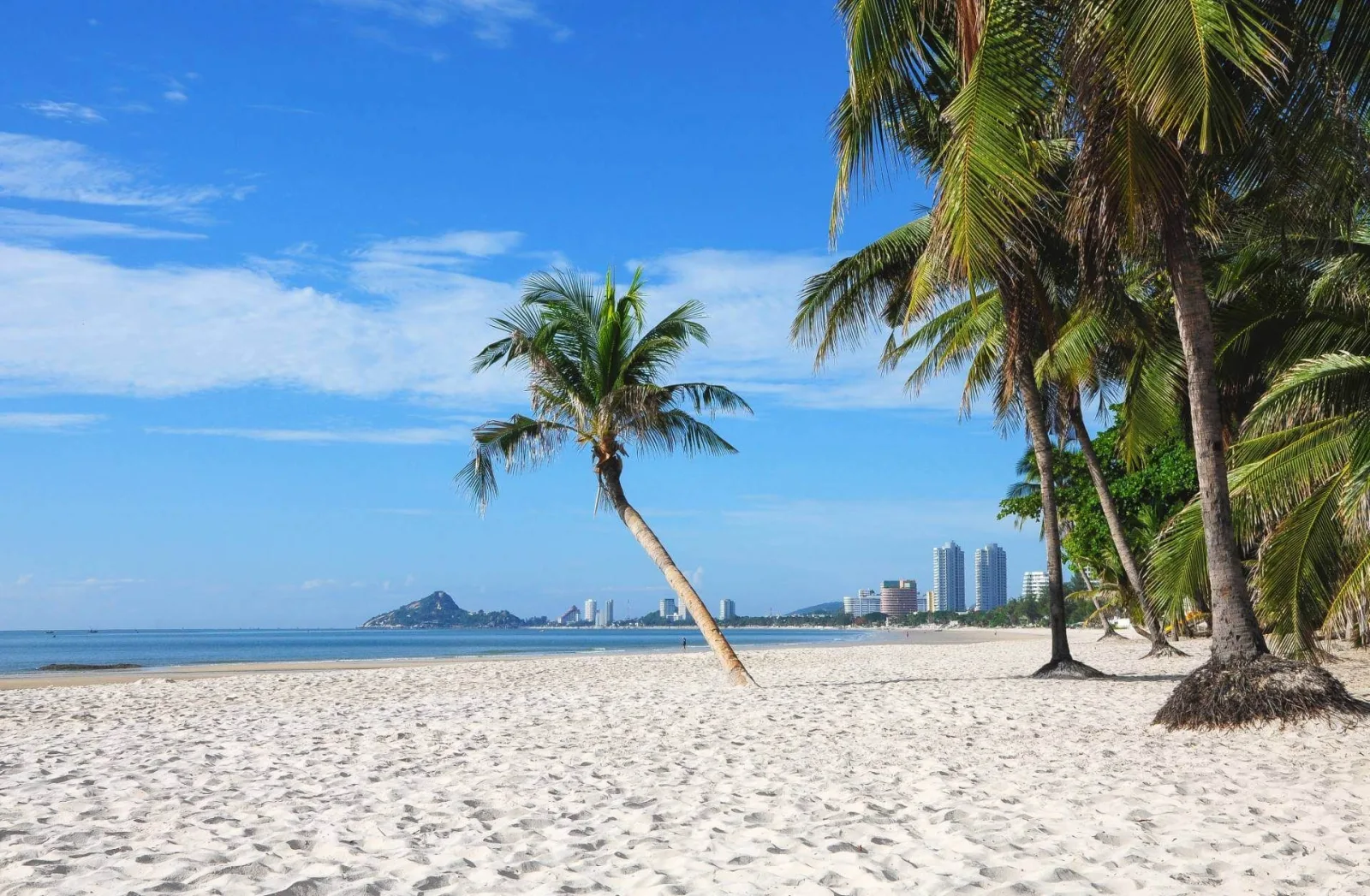 Hua Hin beach with palm trees and the Khao Takiab headland in the distance