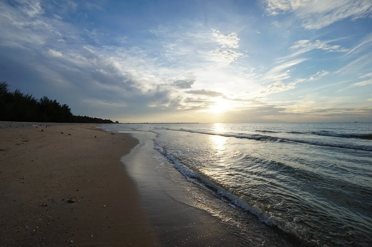 Sunset over a quiet Hua Hin beach lined with casuarina pines